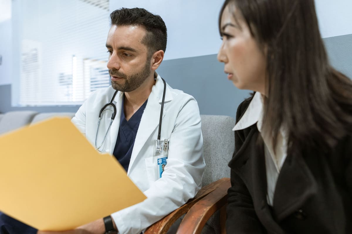 A doctor reviews a folder of prior medical records together with a patient before an examination.